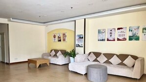 A reception area with two sofas, a small wooden table, and a grey ottoman. - Home Inn Piper Cloud (Xuzhou Dibei Xianghe Branch) (Xuzhou)