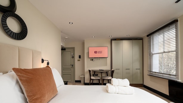 Ein Hotelzimmer mit Bett, Schreibtisch, Fernseher und Kleiderschrank.