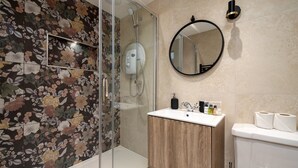 Ein Badezimmer mit Dusche, Waschbecken, Toilette und Spiegel.