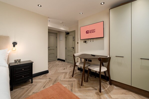 Une chambre d’hôtel comprenant un lit, un bureau avec une chaise, un téléviseur fixé au mur et une armoire.