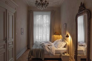 Un dormitorio con cama, candelabro, espejo y lámpara.
