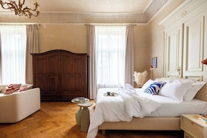 A hotel room with a bed, a sofa, a wooden wardrobe, and a small table.