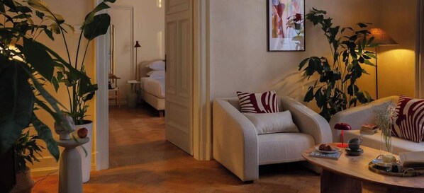 A modern living room with a sofa, armchairs, a coffee table, and potted plants.
