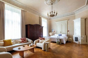 Um quarto espaçoso com uma cama grande, um sofá, uma poltrona, uma mesa de centro e um guarda-roupa.