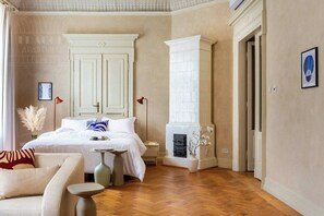 A bedroom with a bed, nightstands, a fireplace, and a door.