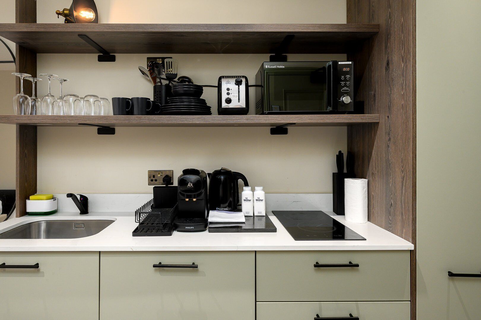 Een kleine keuken met een magnetron, koffiezetapparaat en een spoelbak.
