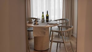 En matplats med ett runt bord, två stolar, en vinflaska, ett glas och en skål.