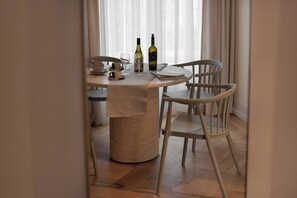 Comedor con una mesa redonda, dos sillas, una botella de vino, una copa y un tazón.