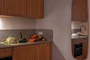 A kitchen with wooden cabinets, a granite countertop, and a bowl of fruit.