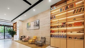 A modern lobby with a wooden bookshelf, comfortable seating, and a large window. - Yoke Hotel (Taiyuan)