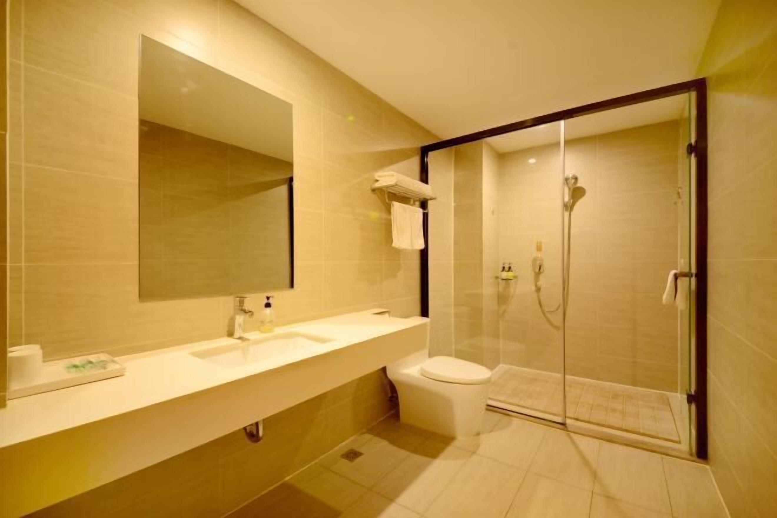 Een moderne badkamer met een grote spiegel, een wastafel, een toilet en een douchecabine.