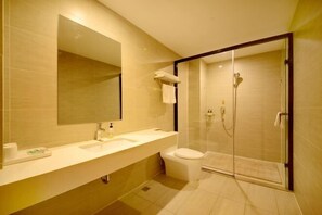 A modern bathroom with a large mirror, a sink, a toilet, and a glass-enclosed shower. - Yoke Hotel (Taiyuan)