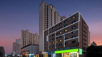 A modern hotel with multiple floors, large windows, and a prominent green sign on the ground floor.