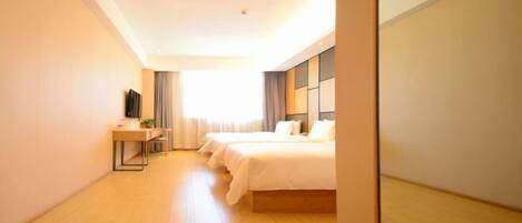 Habitación de hotel con una cama grande, un escritorio con silla, un televisor de pantalla plana y una ventana con cortinas.