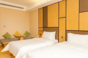 A hotel room with two beds, a small round table, and a sofa with cushions. - Yoke Hotel (Taiyuan)