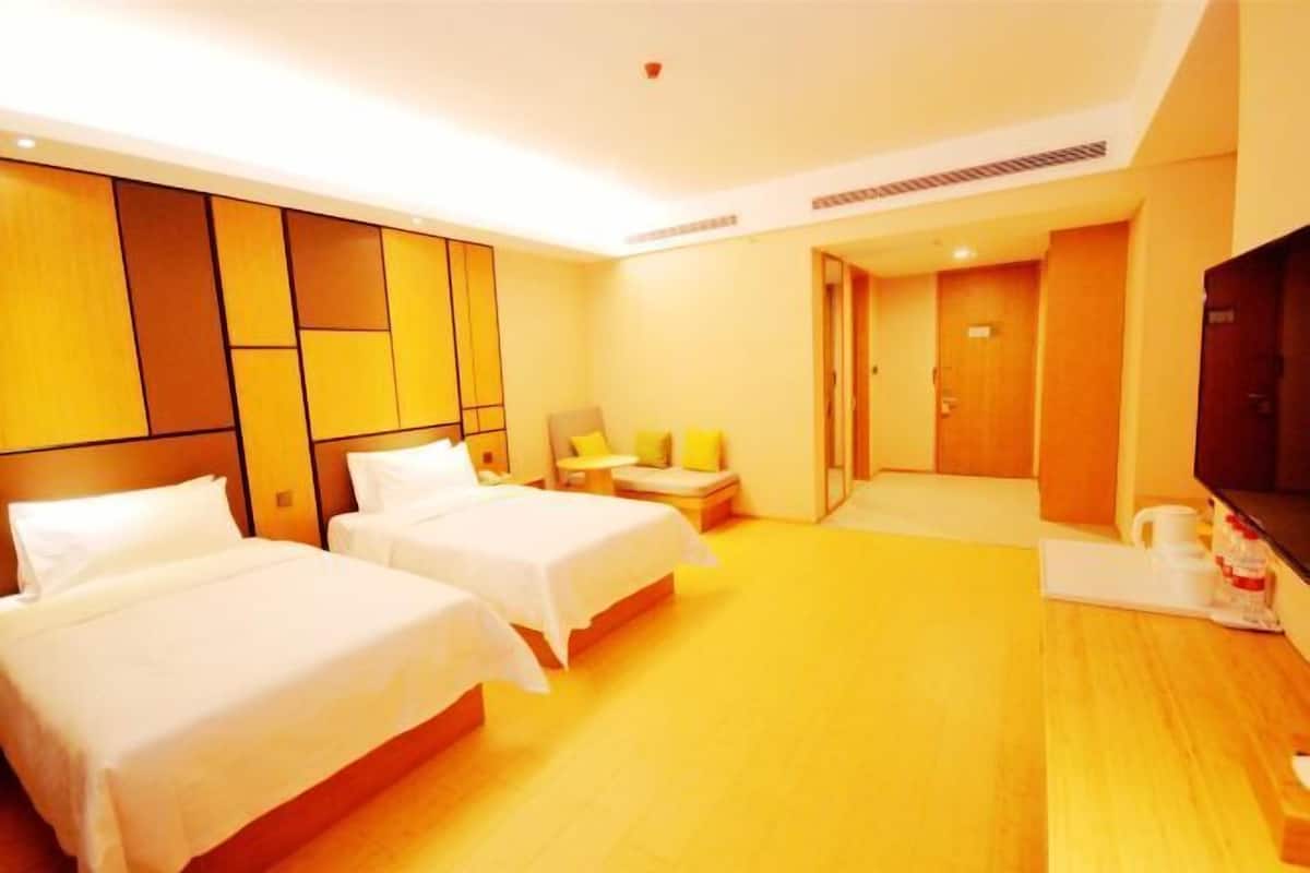 A hotel room with two beds, a television, a desk, and a bathroom.