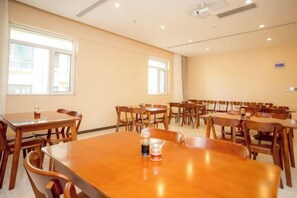 Een vergaderruimte met meerdere tafels en stoelen, grote ramen en een projector aan het plafond.