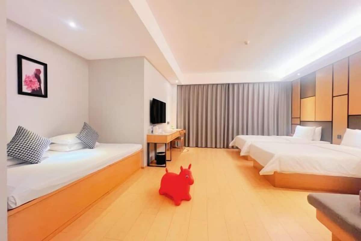 A hotel room with two beds, a desk, a TV, and a red toy horse.