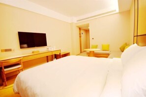 A hotel room with a bed, a desk, a chair, a television, and a small table with chairs. - Yoke Hotel (Taiyuan)