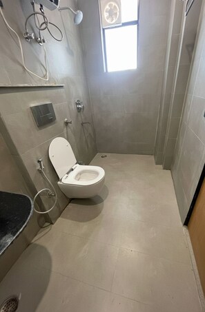 Un baño pequeño y moderno con inodoro, ducha y ventana.