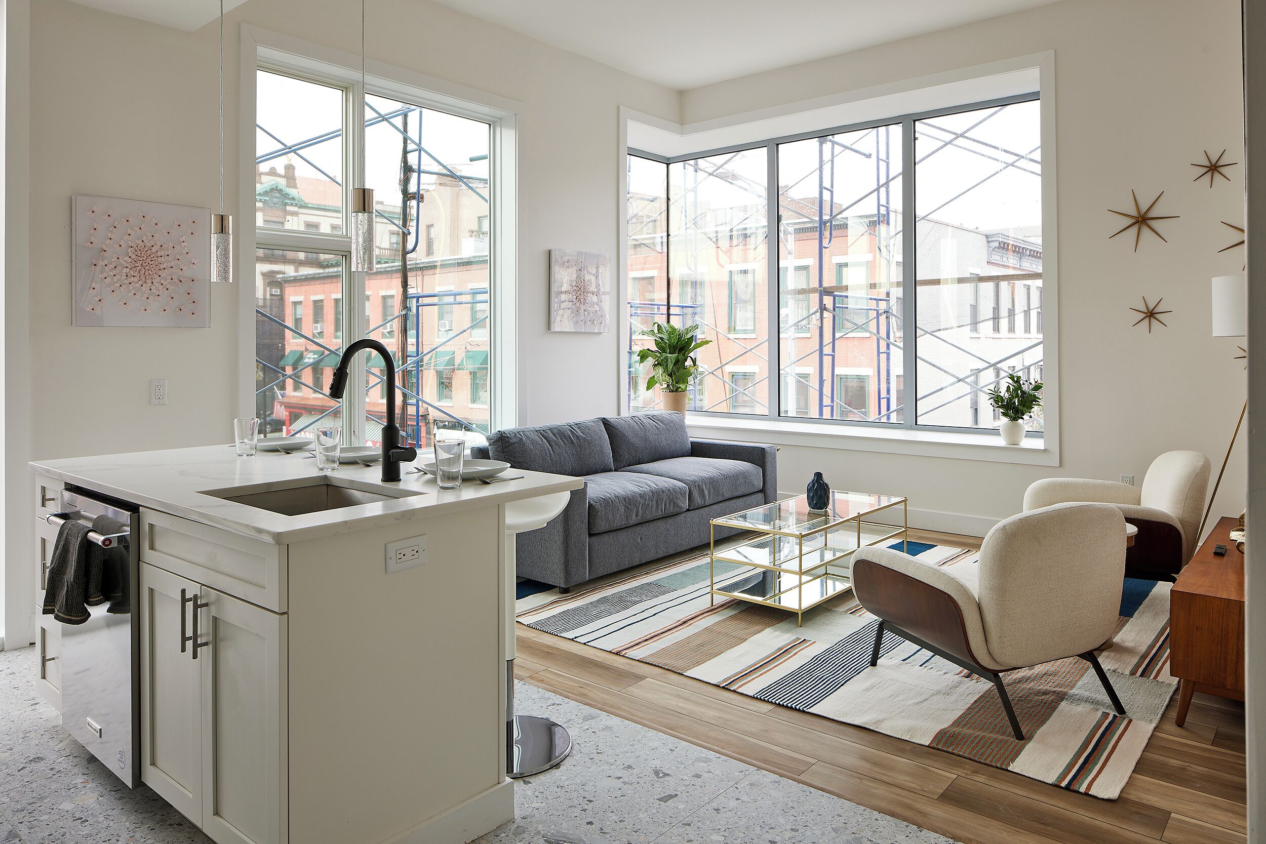 A modern kitchen with a built-in island, a gray sofa, and a glass coffee table.