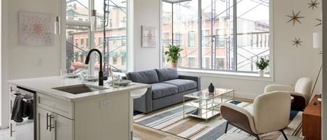 A modern kitchen with a built-in island, a gray sofa, and a glass coffee table.