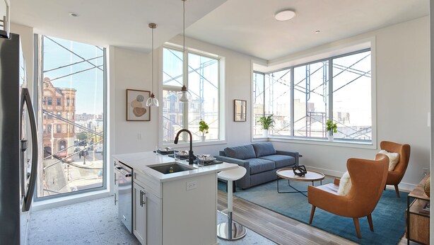 Un apartament modern amb una illa de cuina, un sofà i una zona de menjador.