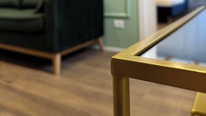 Ein modernes Wohnzimmer mit einem grünen Sofa, einem Couchtisch und gerahmten Kunstwerken an der Wand.