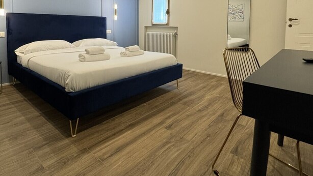 Ein Schlafzimmer mit einem Bett, einem Heizkörper, einem Spiegel und einem Tisch.