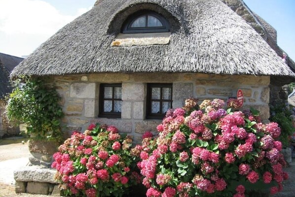 A stone cottage with a thatched roof and two windows. - Cottage in the heart of the village of Kerascoët. (NEVEZ)
