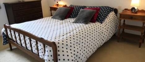Ein Schlafzimmer mit einem Bett, zwei Nachttischen, einer Kommode und Wandlampen.