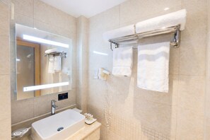 Een moderne badkamer met een grote spiegel, een wastafel, een handdoekrek en een verwarmde handdoekstang.