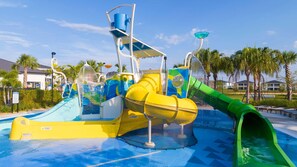 Un parco acquatico con diverse scivolate e giochi d'acqua, immerso tra palme e edifici.