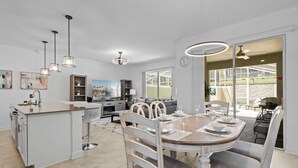 Una cucina moderna con isola centrale, zona pranzo con tavolo e sedie rotonde, e vista sul patio esterno.