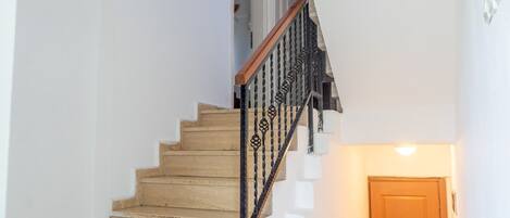 Una escalera de madera con barandillas de metal negro que conduce a una plataforma.