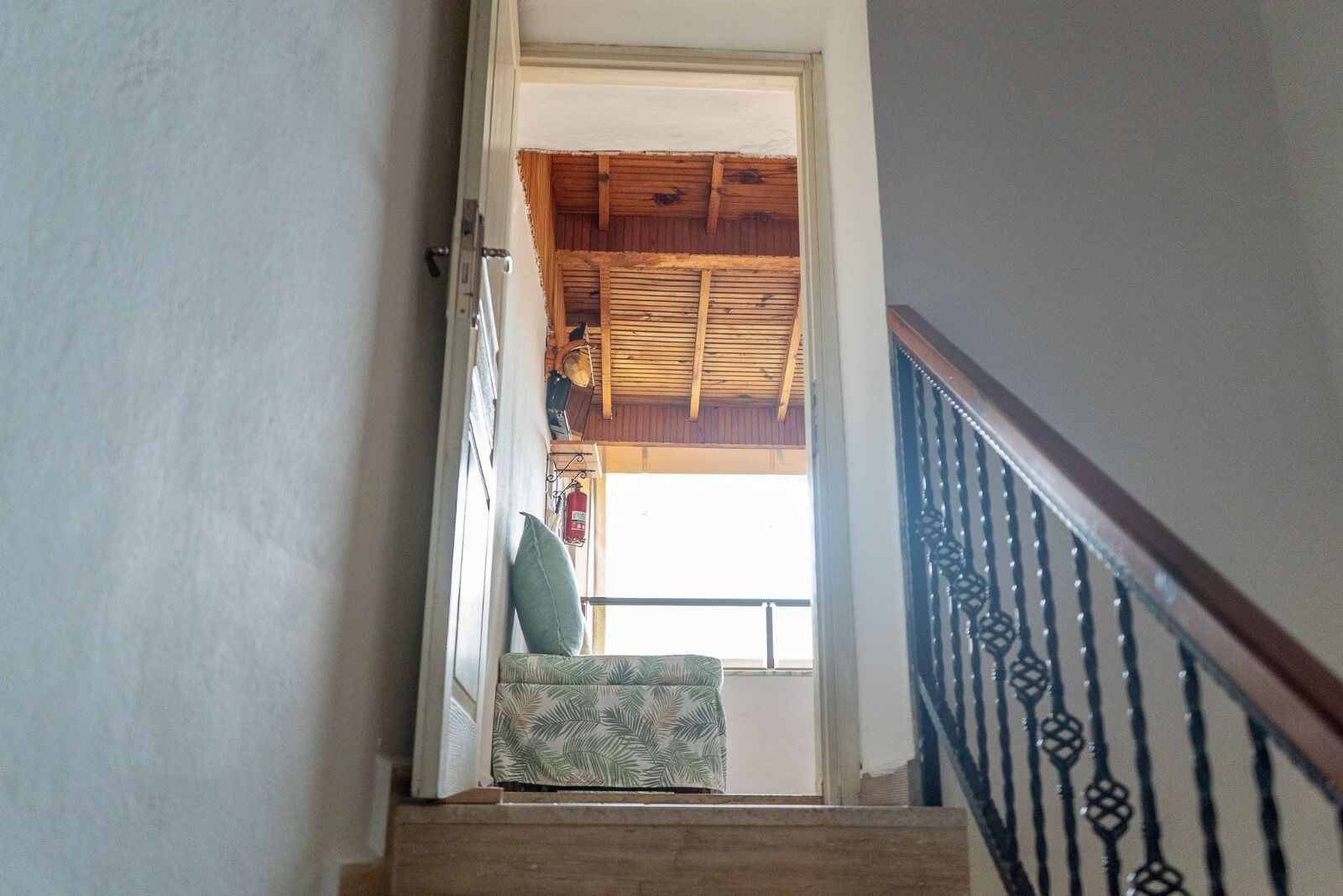 A staircase leading to a room with a wooden ceiling and a view of the outside.