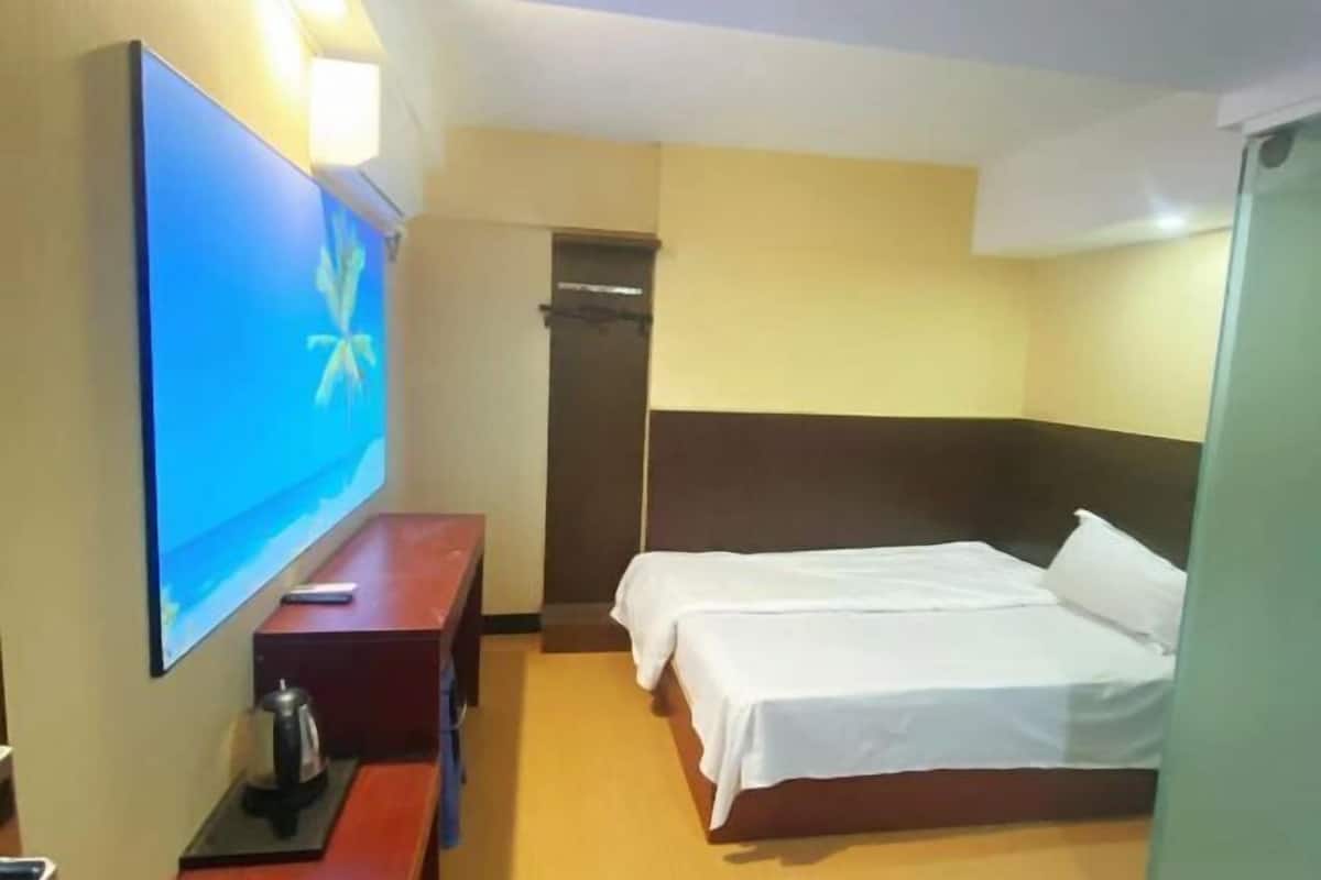 A hotel room with a bed, a desk with a coffee maker, a TV, and a wardrobe.
