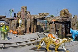 A zoo enclosure with a cheetah, a giraffe, and a blue elephant statue. - Huile Holiday Hostel (Shanghai)