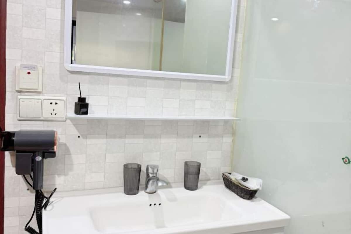 A bathroom with a white sink, a mirror, a towel rack, and a soap dispenser.