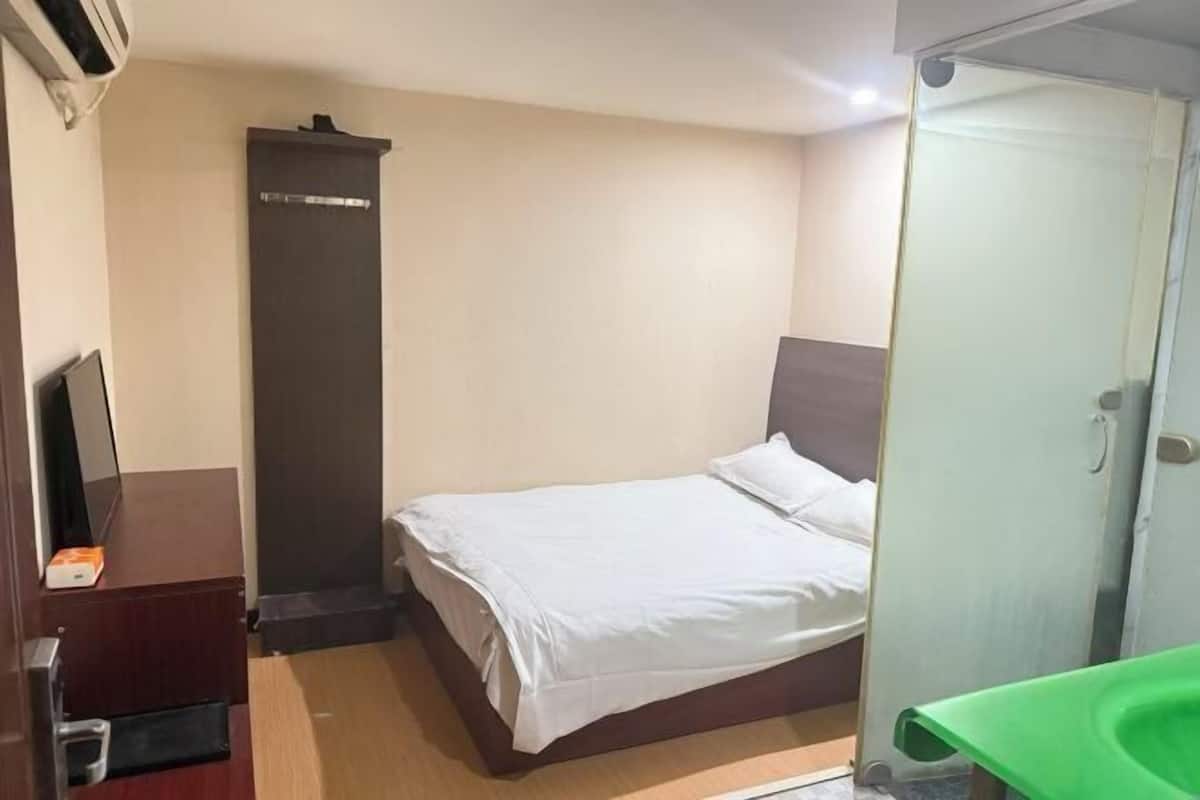 A hotel room with a bed, a desk, a wardrobe, and a bathroom.