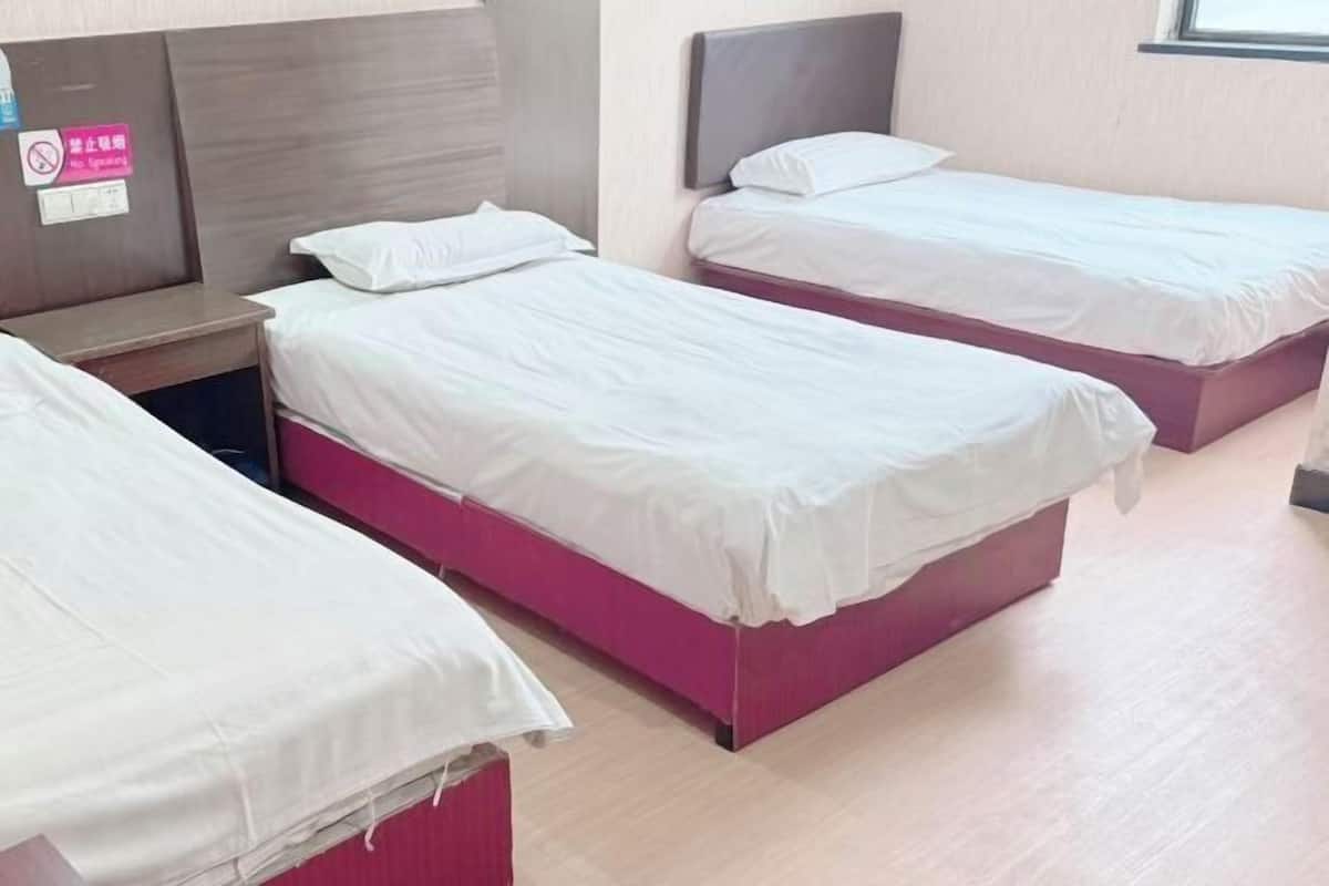 A hotel room with three beds, each with white bedding and pink headboards.