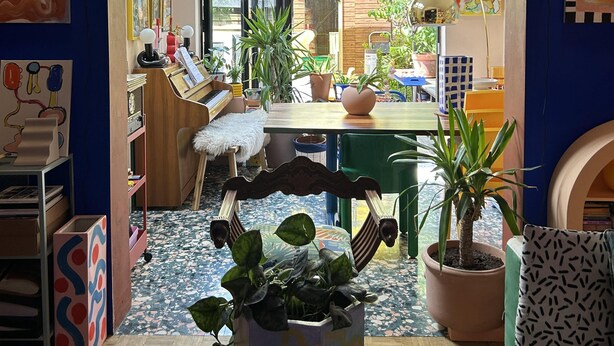 Ein Zimmer mit Holzboden, einem Esstisch, Stühlen, einem Klavier und verschiedenen Kunstwerken an den Wänden.