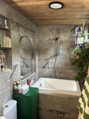 Ein modernes Badezimmer mit freistehender Badewanne, einer Duschbrause und einem Spiegel.