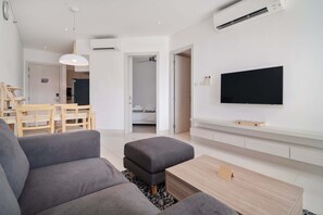 Un salon moderne avec un canapé gris, une table basse en bois et un téléviseur à écran plat fixé au mur.
