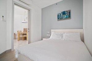 Een moderne slaapkamer met een groot bed, een zithoek met een tafel en stoelen, en een fiets schilderij aan de muur.