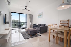 Un salon moderne comprenant un canapé, un pouf, une table à manger, des chaises et un ventilateur de plafond.