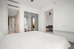 Ein Schlafzimmer mit einem großen Bett, einer Duschkabine und Blick auf einen Balkon.