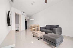Un salon moderne avec un canapé gris, une table basse en bois et un coin repas comprenant une table et des chaises.