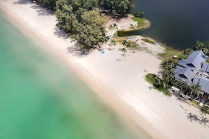 An aerial view of a beach with a house and palm trees.
