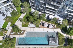A rooftop pool with a glass enclosure, surrounded by greenery and modern buildings. - Cassia Residences, Two-Bedroom 1502 D Deluxe Lake (Choeng Thale)